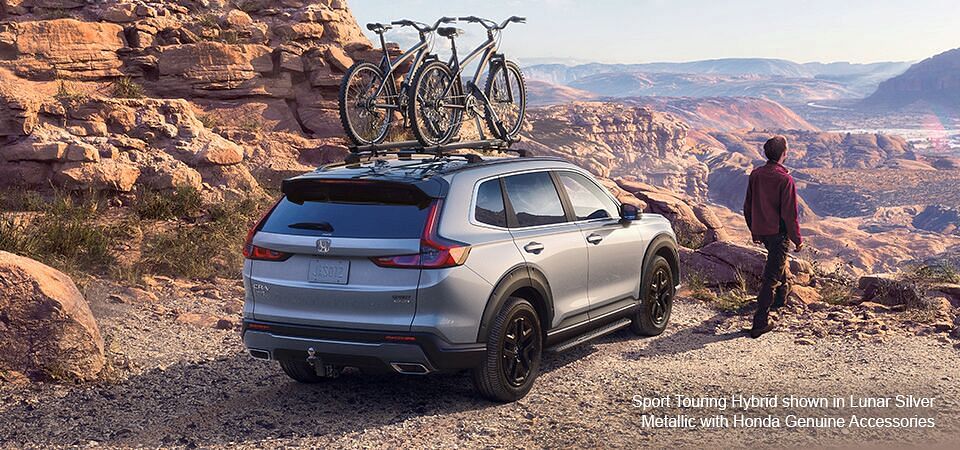 A Lunar Silver Metallic Honda Sport Touring Hybrid with Honda Genuine Accessories standing on the edge of a cliff, the valley in the background.