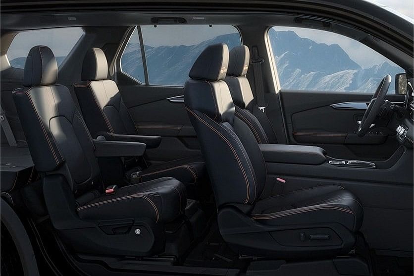 Interior view of a 2025 Honda Pilot showcasing black leather seats with orange stitching, designed for comfort and style, against a mountainous backdrop.