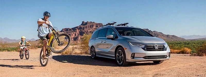 New 2023 Honda Odyssey parked on desert with cyclist on the left