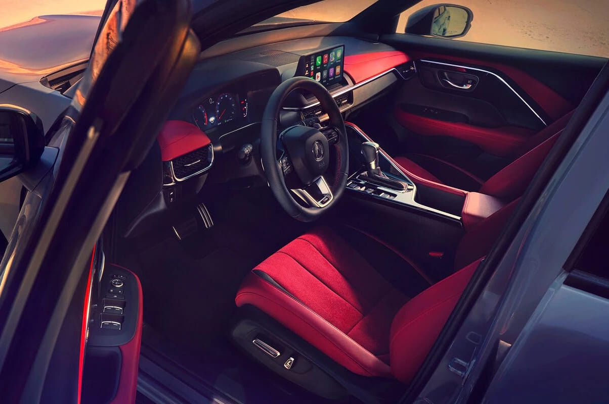 Sleek 2026 Acura ADX interior with bold red and black seats, digital dashboard, and touchscreen displaying apps, exuding a modern and sporty vibe.