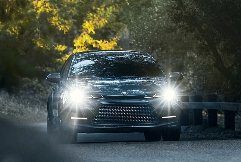 2022 Toyota Corolla driving through mountains at sunset while adaptive front lights follow every turn for visibility