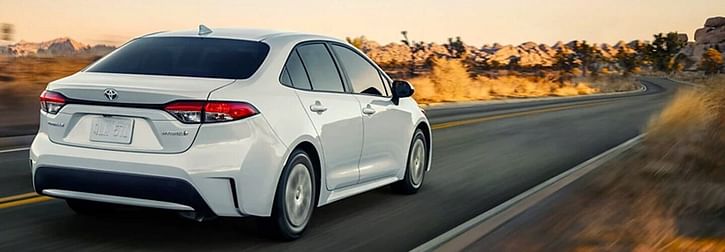 White 2022 Toyota Corolla Hybrid driving at dusk