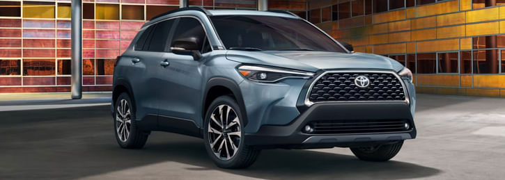 A blue SUV parked indoors, showcasing its front and side profile with alloy wheels and a shiny grille.