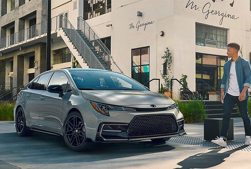 Man walking by admiring a 2022 Corolla XSE Apex Edition parked in front of a building