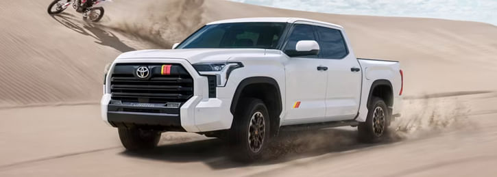 A white Toyota Tundra driving through a sandy desert