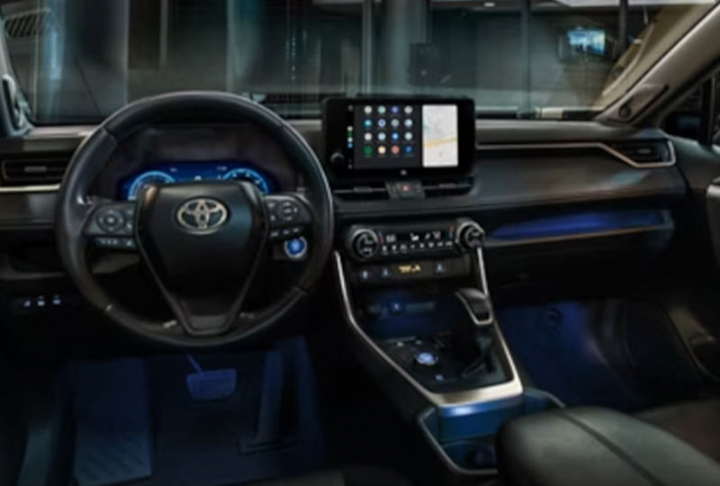 Interior view of a Toyota RAV4 dashboard and center console at night, illuminated by blue ambient lighting, with Android Auto displayed on the infotainment screen.