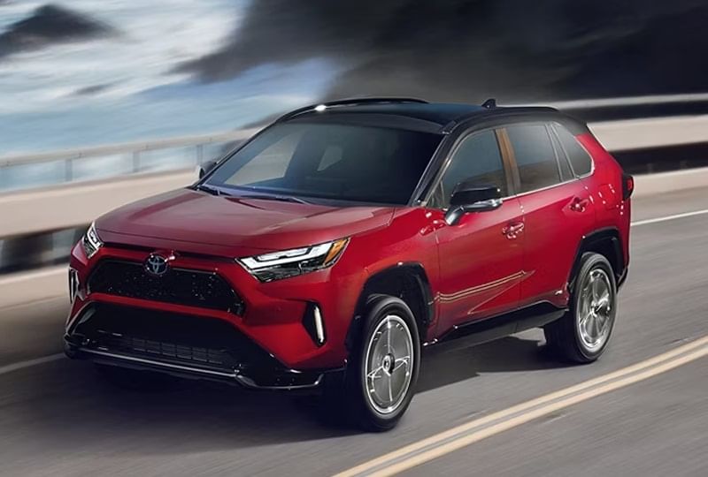 A Toyota driving along a scenic road surrounded by trees and greenery.