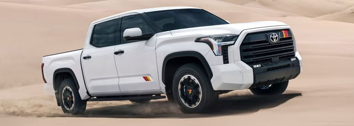 A white Toyota Tundra driving through a sandy desert
