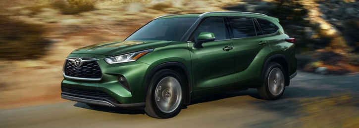 A green Toyota Highlander driving on the road