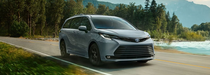 A 2025 Toyota Sienna navigates a winding mountain road, showcasing its sleek design against a scenic backdrop.