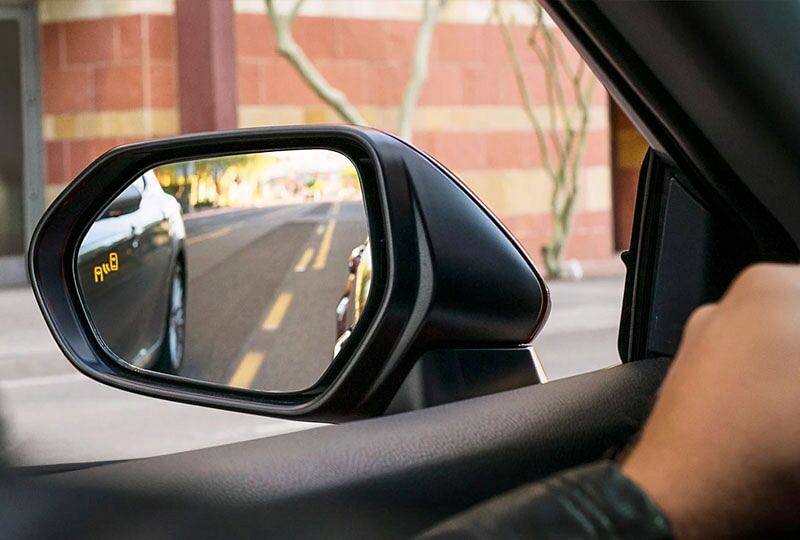 A car is in the driver's blind spot and the safety technology is notifying him