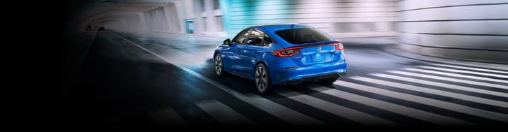 The 2025 Honda Civic Hatchback Sport Touring Hybrid in Boost Blue Pearl driving through underground tunnel