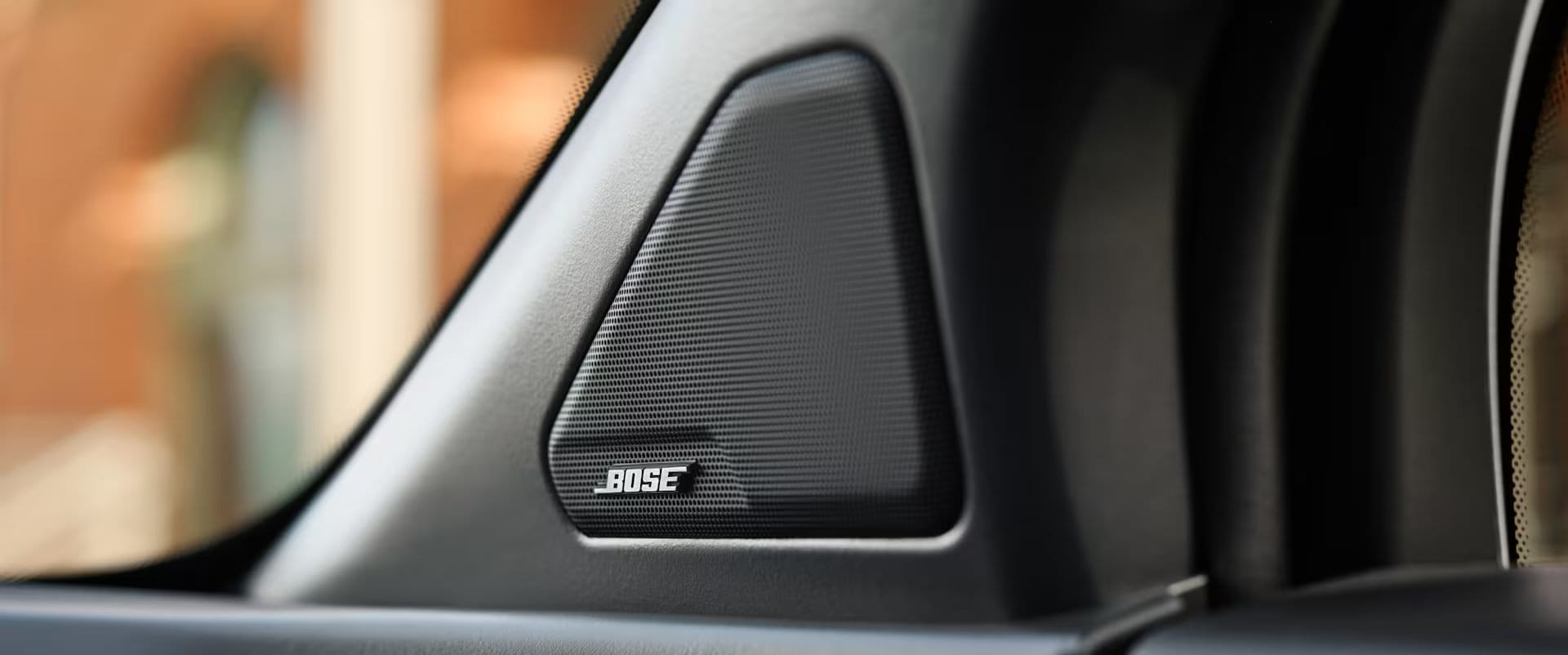 Close-up view of a triangular Bose speaker grille, featuring the Bose logo, mounted inside the 2025 Honda Prologue