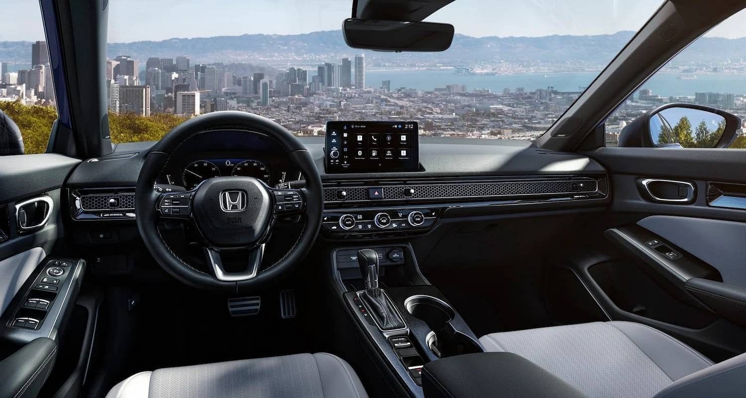 The 2025 Honda Civic Sedan Sport Touring Hybrid in Blue Lagoon Pearl, interior of vehicle at driver POV angle in urban overlook environment