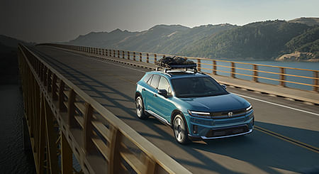 A green prologue driving on a bridge with cargo on the roof.