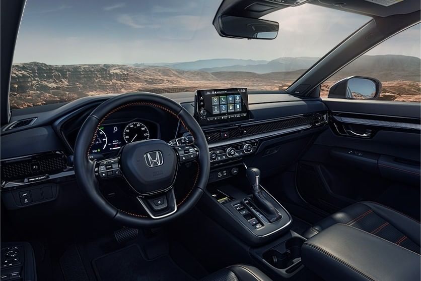 Interior view of a used Honda CR-V Hybrid, featuring a sleek dashboard, digital display, and leather seats with sporty accents.