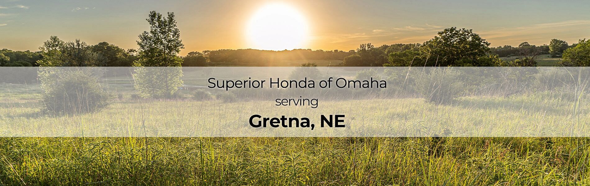 In the background meadow with the setting sun with text in the front: SUperior Honda of Omaha serving Grenta, NE