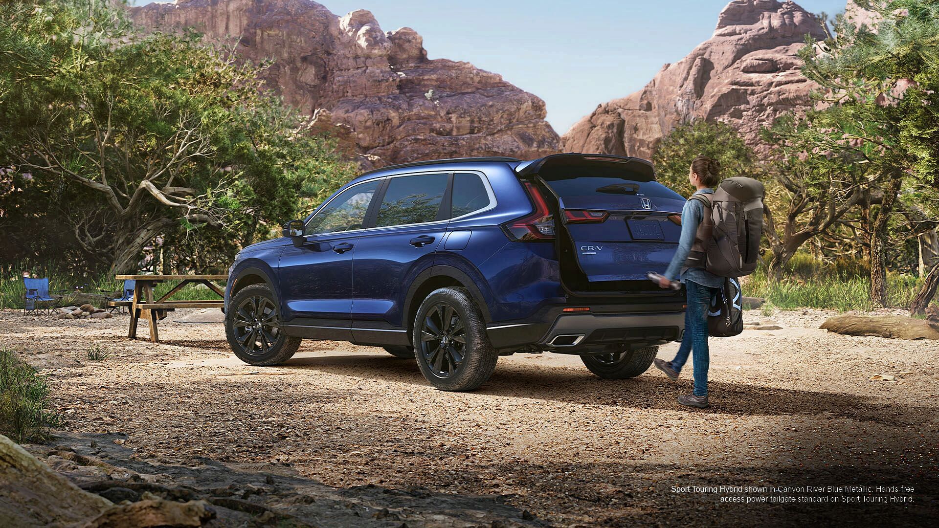 Woman opening trunk with hands-free feature in Sport Touring Hybrid shown in Canyon River Blue Metallic.