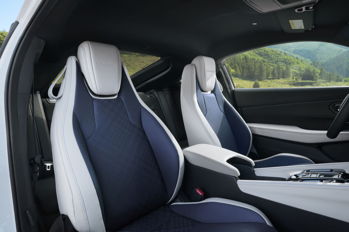 A close-up of the two-tone blue and white front sport seats in the 2026 Honda Prelude, featuring integrated headrests with the Prelude name embossed on them.