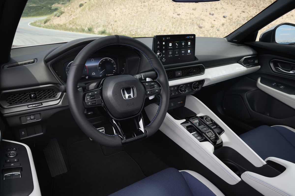 The driver-focused cockpit of the 2026 Honda Prelude, highlighting the flat-bottom steering wheel with blue accent stitching and the clear digital instrument and infotainment displays.