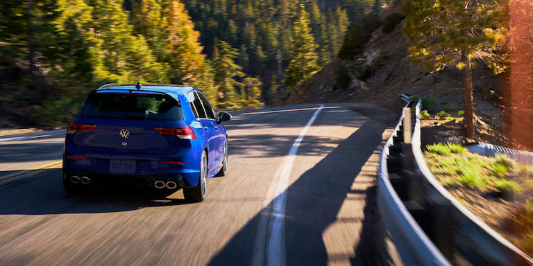 Blue Volkswagen car driving through a scenic landscape
