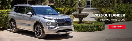 A silver 2023 mitsubishi outlander standing next to a fountain. Park in the background