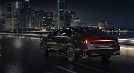 A black Hyundai Sonata driving through the city at night.