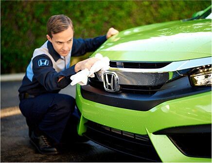 Service technician polishes the front of a green honda