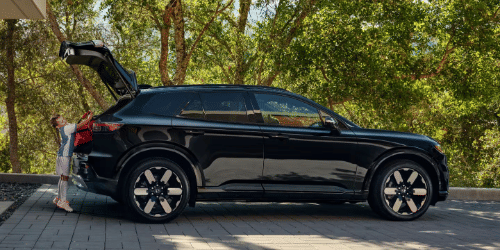 2026 Honda Prologue Elite en Raven Black, estacionado en casa con el portón abierto, mientras un niño se acerca a la parte trasera del vehículo para cargar equipo de fútbol para un partido.