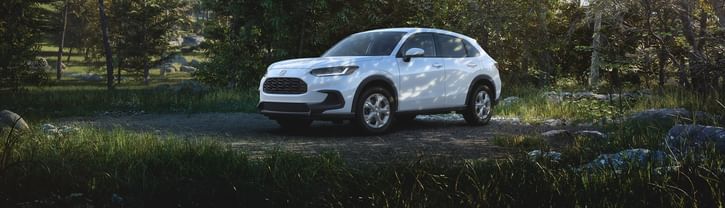 Front driver-side view of the 2026 Honda HR-V LX in Platinum White Pearl shown parked in a forested setting