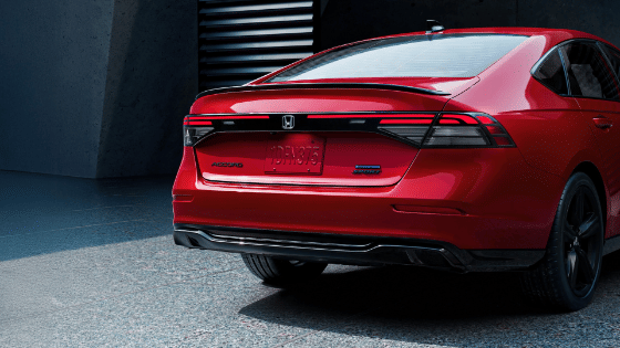 Rear Passenger 7/8 of 2026 Honda Accord in Radiant Red Metallic in minimalistic urban courtyard environment, showing LED taillights.