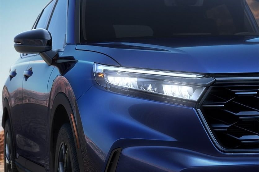 Primer plano del elegante frente azul del Honda CR-V Hybrid 2025, mostrando los faros LED elegantes y elementos de diseño modernos contra un cielo despejado.