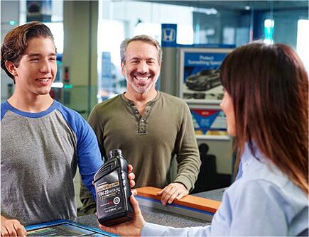 saleswoman gives motor oil to young man