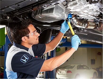 The service technician looks at the manifold of the exhaust system