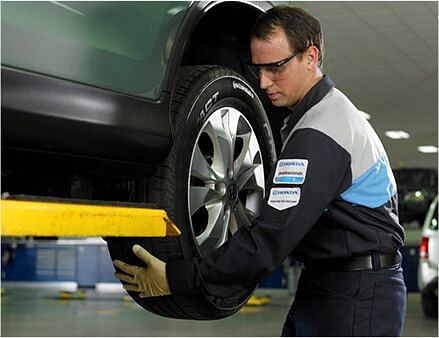 serviceman putting a wheel on a green honda