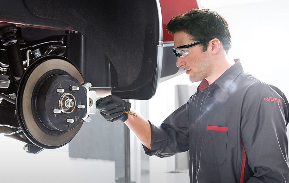 A man with glasses and a black shirt is engaged in fixing a brake, demonstrating expertise in automotive repair.