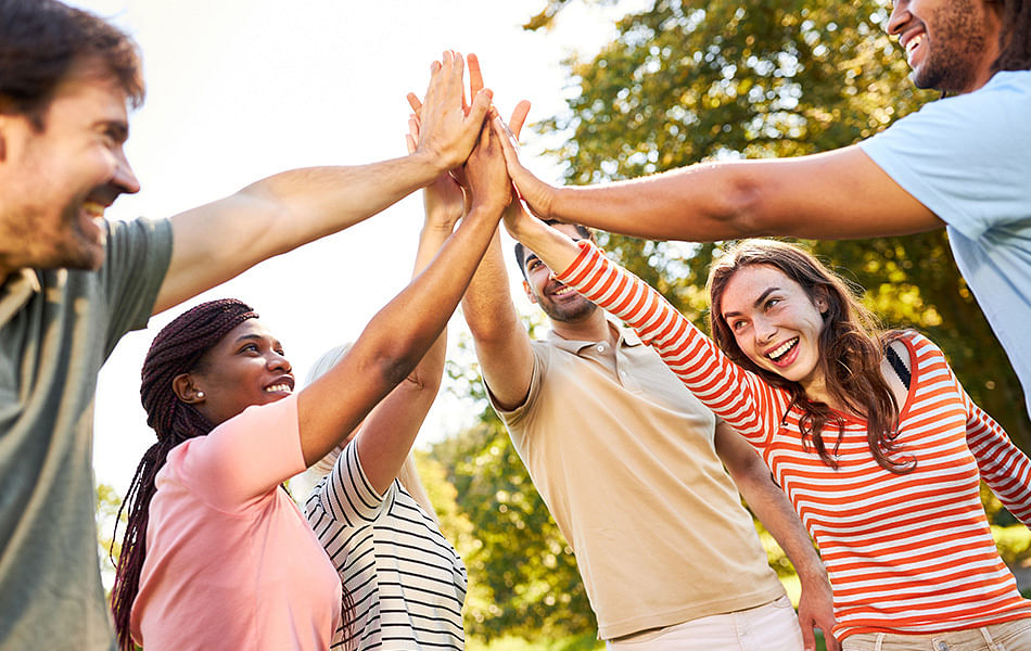 A diverse group of individuals joyfully exchanging high fives in a celebratory atmosphere.