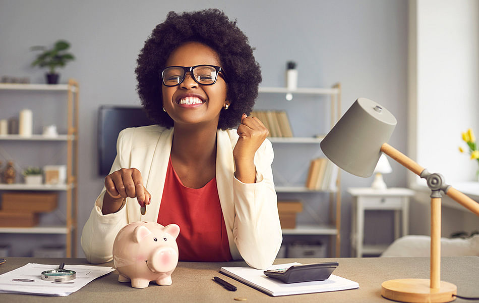 A woman in glasses interacts with a piggy bank, illustrating the importance of saving and managing finances effectively.