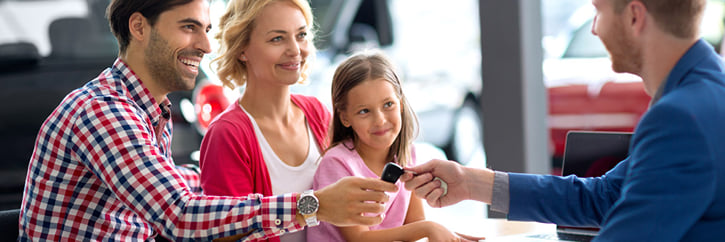 Happy family receiving car keys from salesperson in dealership