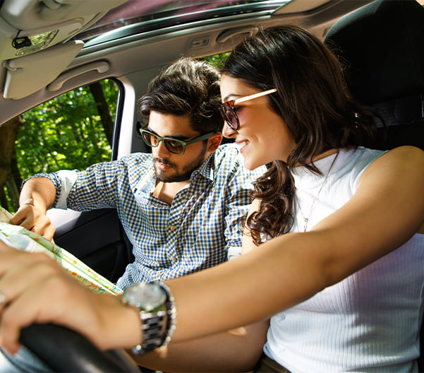 Couple in car looking at a map, planning their road trip.