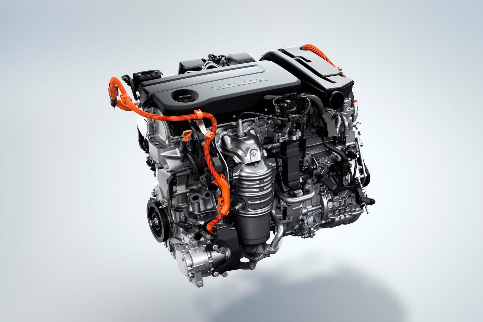 Primer plano de un motor de automóvil moderno con componentes metálicos visibles y cables de color naranja brillante, con el nombre de la marca, sobre un fondo claro.