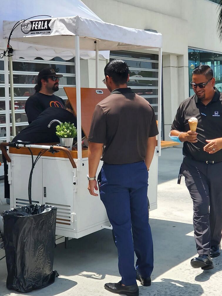 Employees stand by the ice cream cart and smile