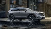 A Sport Touring Hybrid Honda with AWD shown in Urban Gray Pearl driving on the street in rains. Buildings in the background