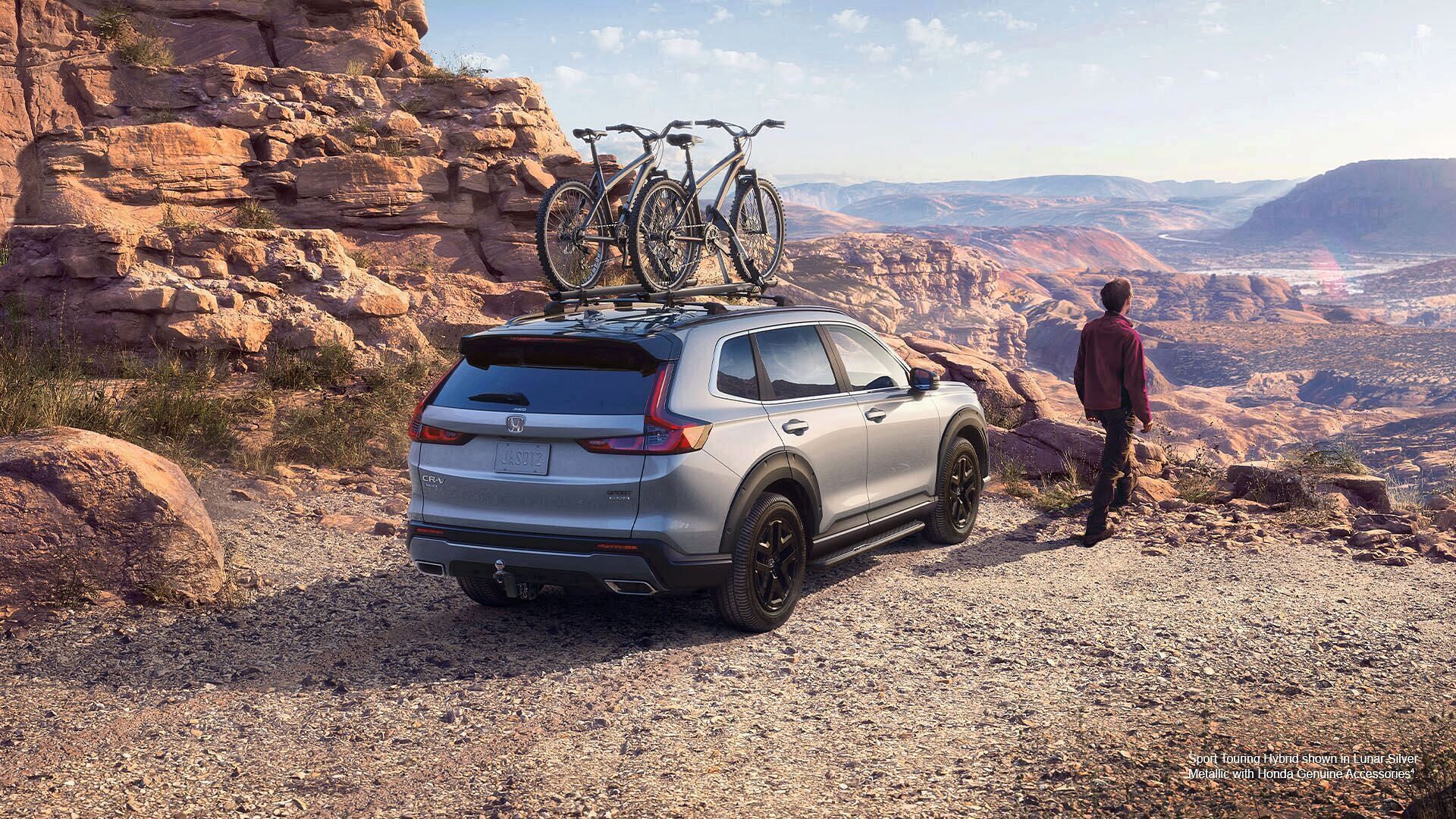 A Lunar Silver Metallic Honda Sport Touring Hybrid 2023 with Honda Genuine Accessories standing on the edge of a cliff, the valley in the background.