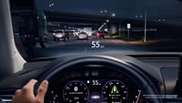 The view from the perspective of a driver driving on the highway at night with the Digital Instrument Cluster and Head-Up Display turned on