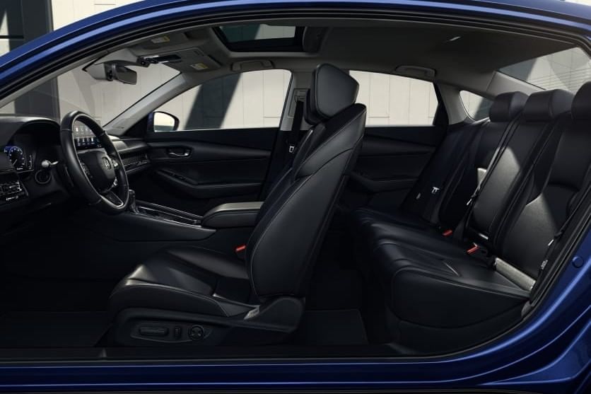 Interior view of a 2025 Honda Accord Hybrid showcasing black leather seats, a sleek dashboard, and ambient lighting, highlighting a spacious layout.