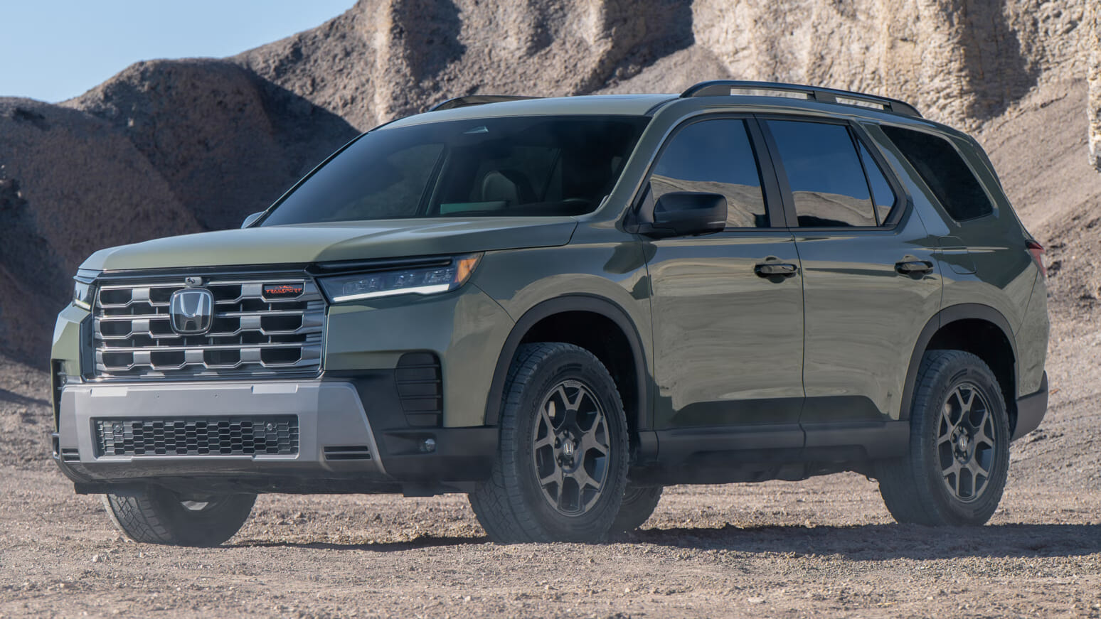 SUV verde estacionado en un paisaje rocoso del desierto. El diseño robusto del vehículo y la superficie brillante se destacan contra el terreno accidentado, emanando fuerza y confiabilidad.