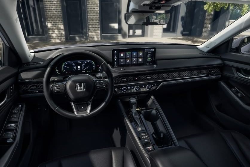 Interior view of a 2025 Honda Accord Hybrid showcasing a modern dashboard, touchscreen display, steering wheel, and leather seats.