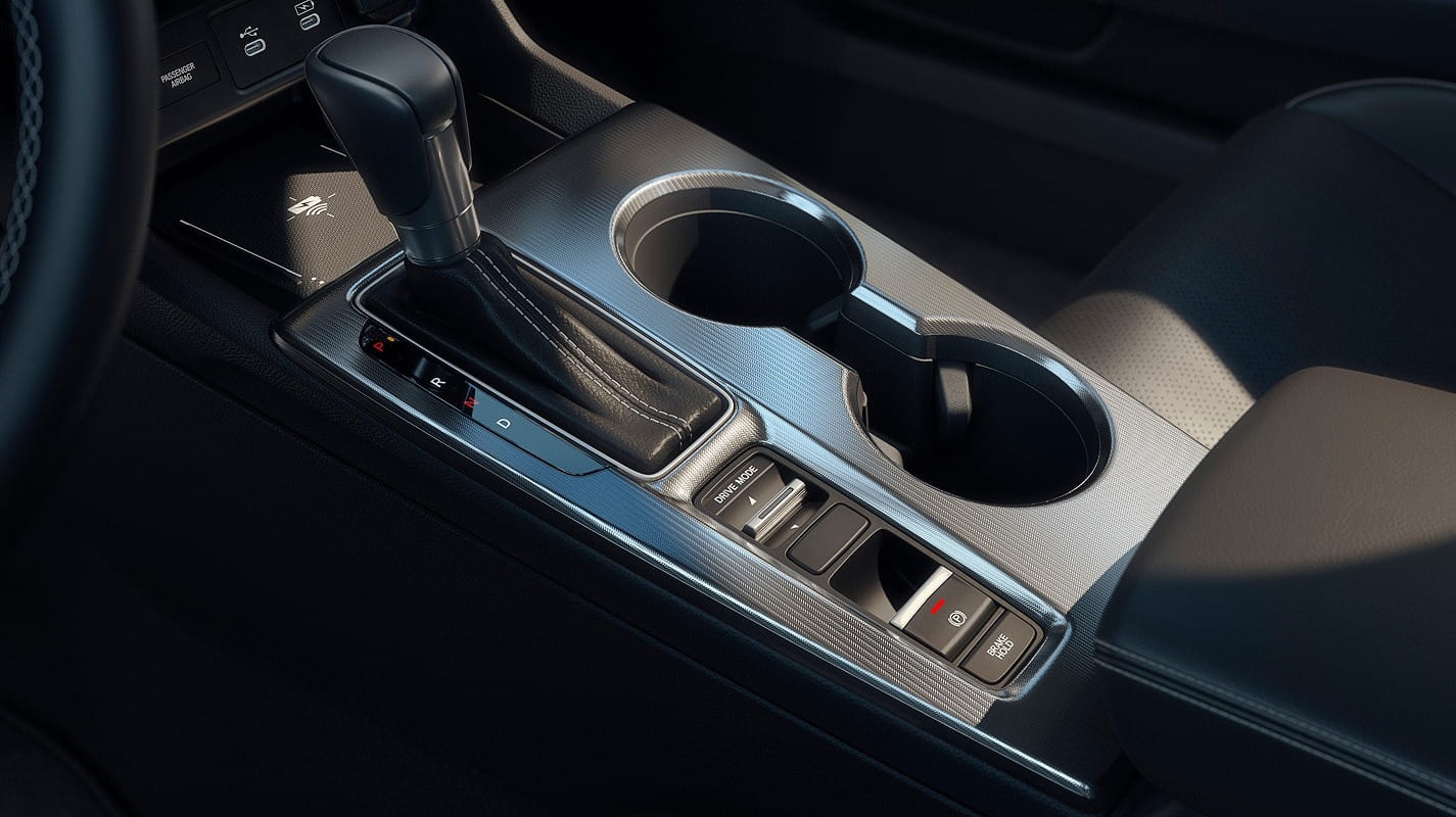 The image shows a 2026 Honda Civic Hatchback Hybrid central console with a gear shifter, two cup holders, and buttons for seat heating and driving modes. The interior is sleek and modern.