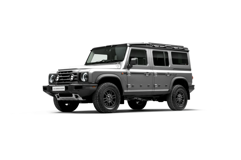 Silver Ineos Grenadier Station Wagon. Features include a four-door cab, off-road tires, and a visible spare tire.